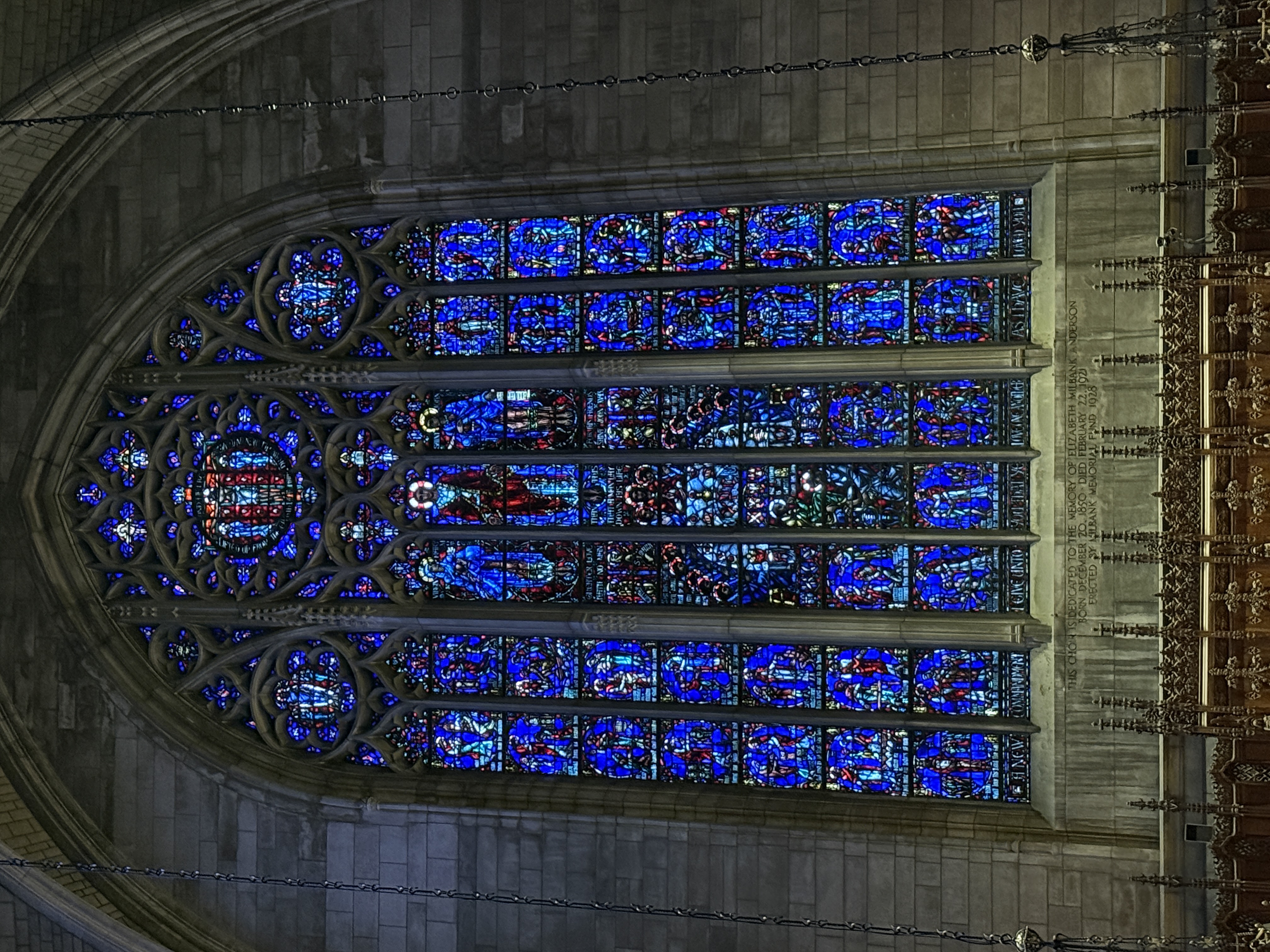 Large Gothic window set beneath a tall stone arch and hanging chains