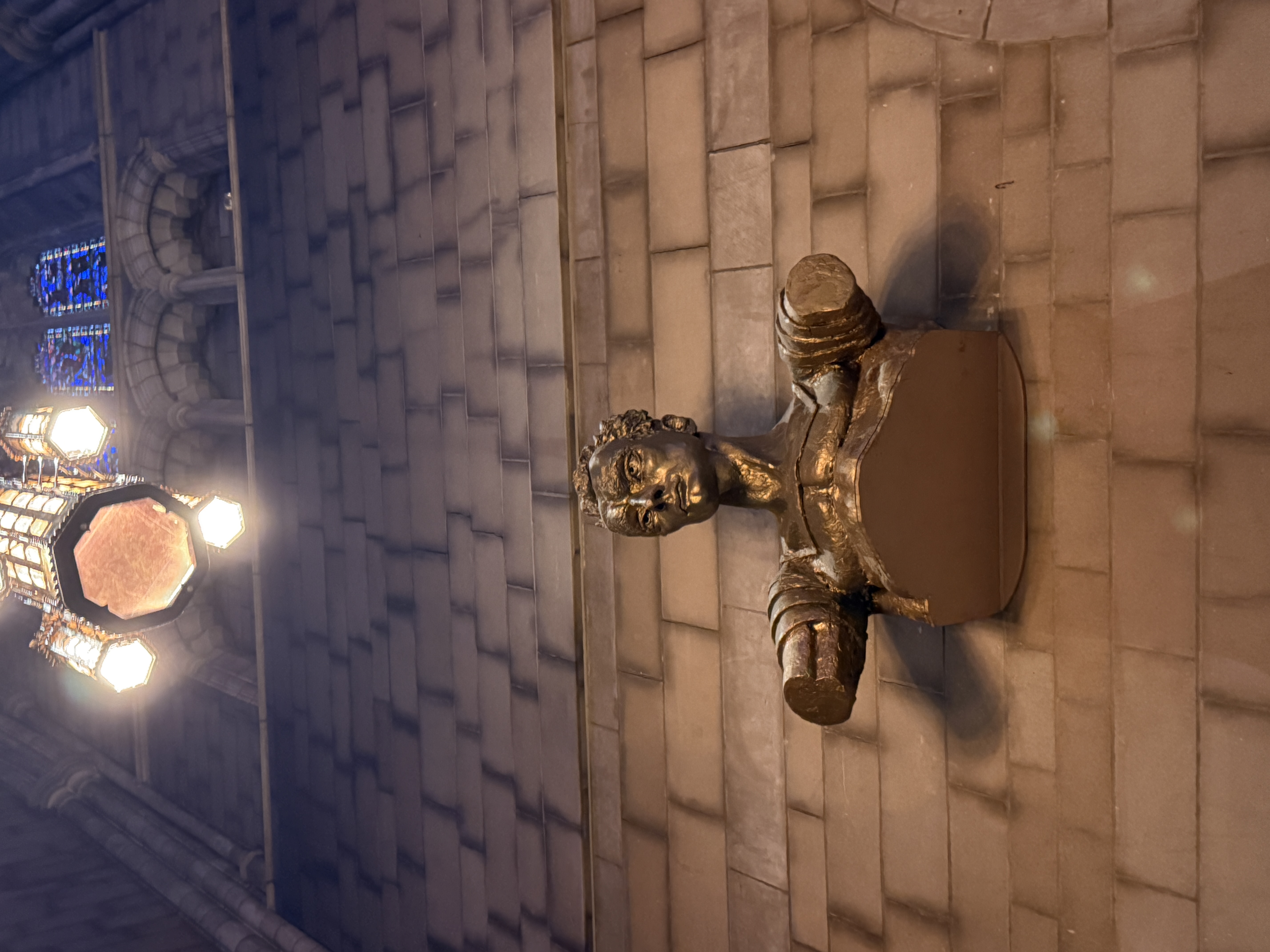 Abstract dark bronze sculpture displayed on a wooden ledge inside the chapel