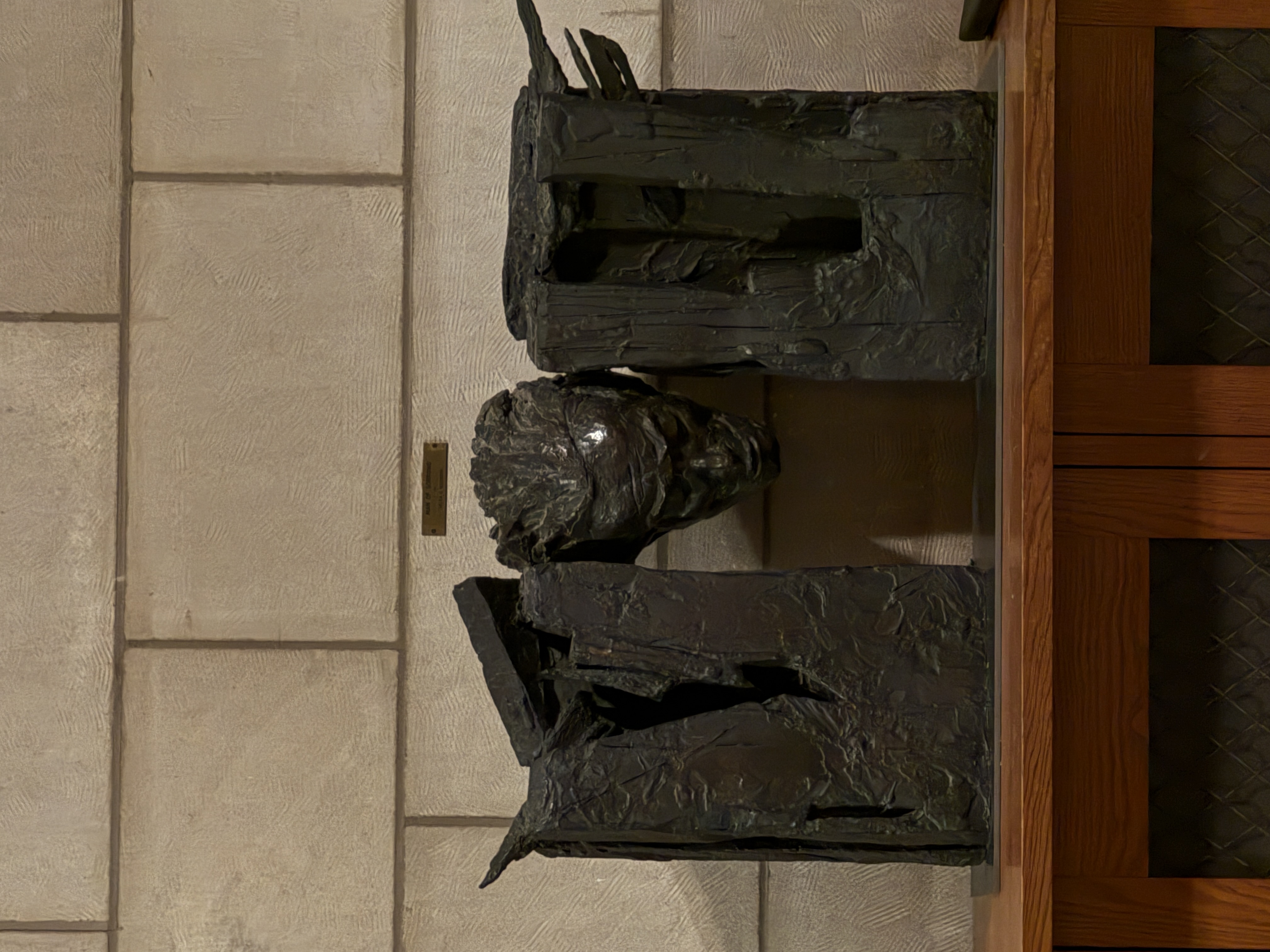 Bronze wall-mounted bust sculpture beneath a hanging lantern