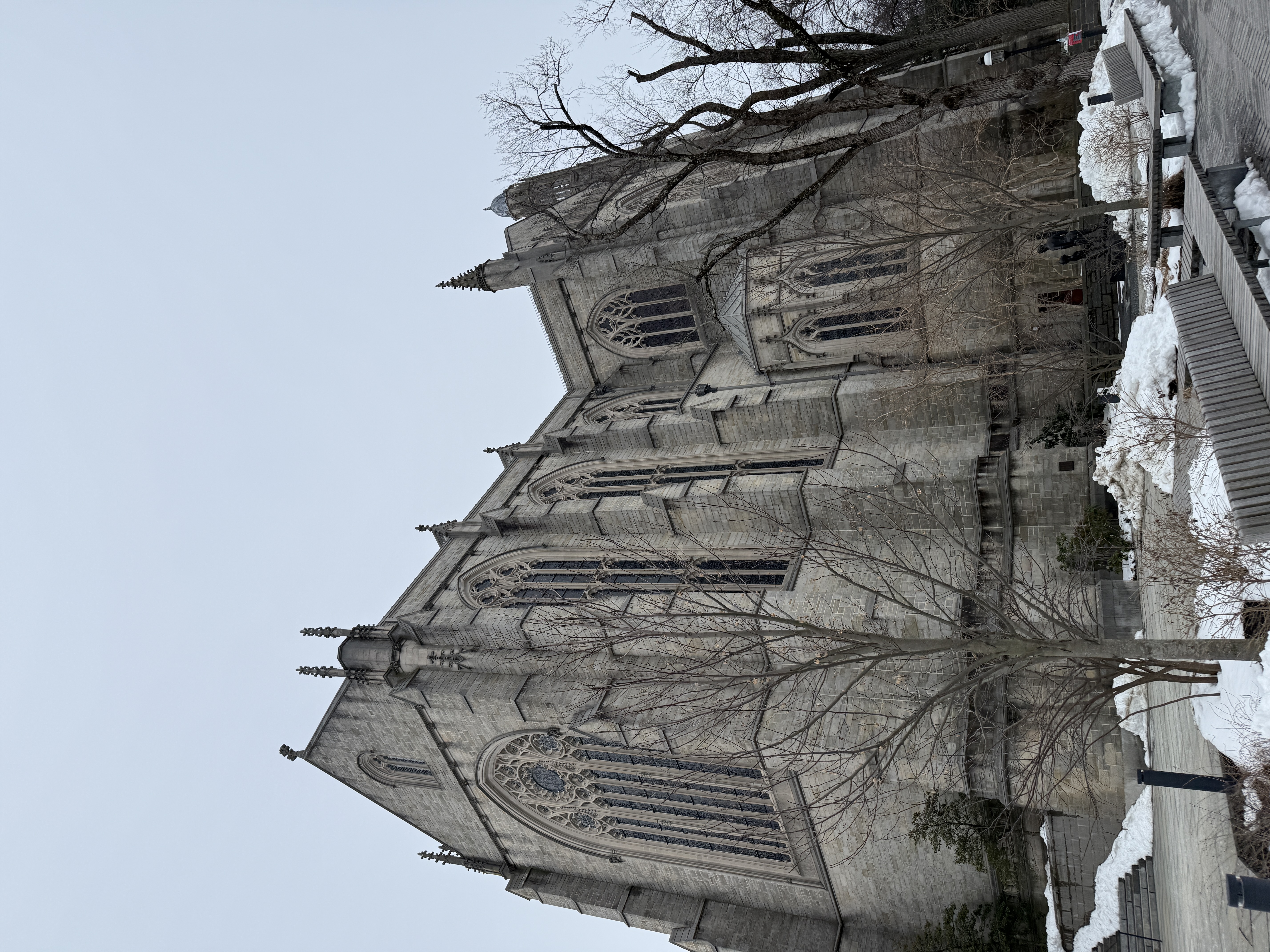 Stone chapel wall beside a snowbank near a narrow exterior doorway