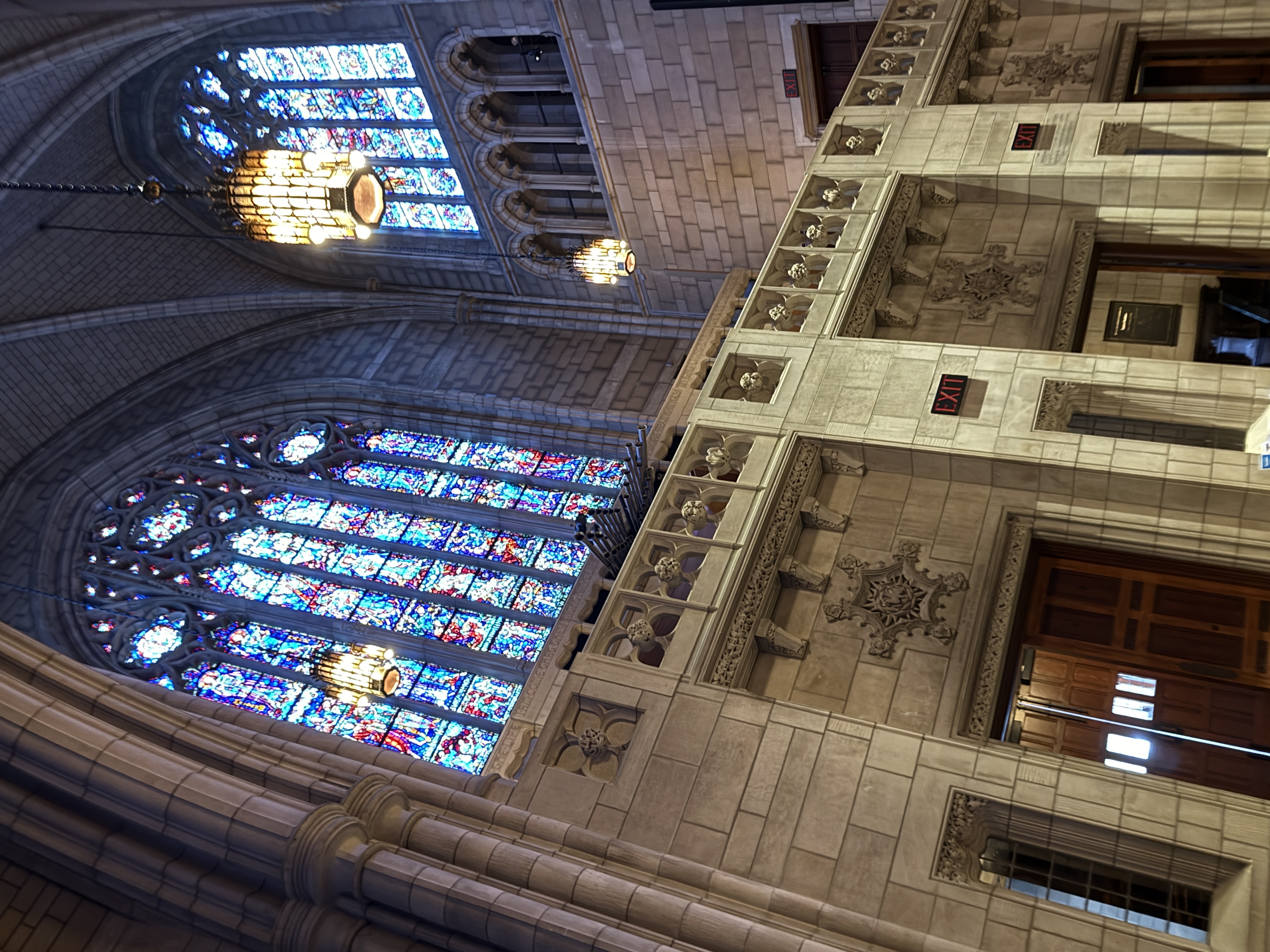 Vaulted chapel interior ceiling with hanging lantern, wooden doors, and illuminated exit sign