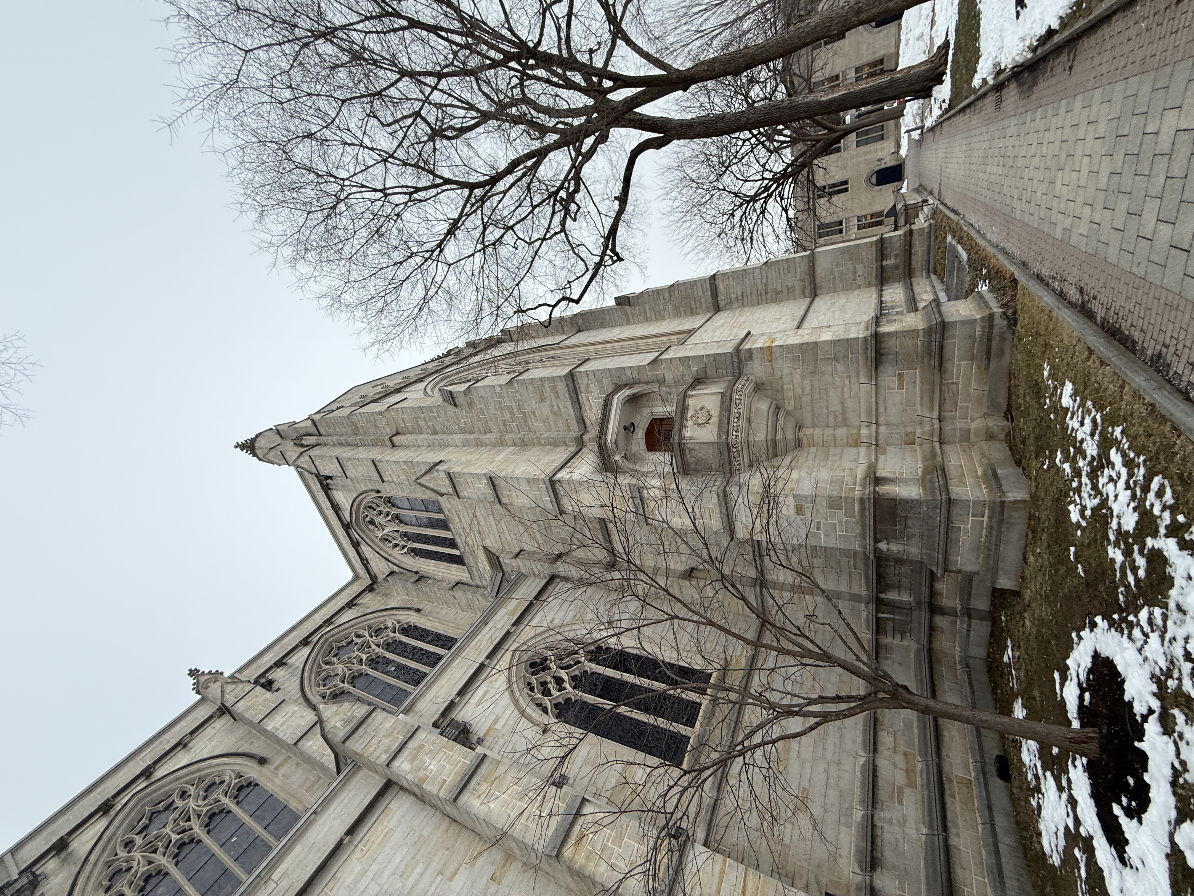 Wide side view of the chapel exterior with leafless trees and a paved walkway