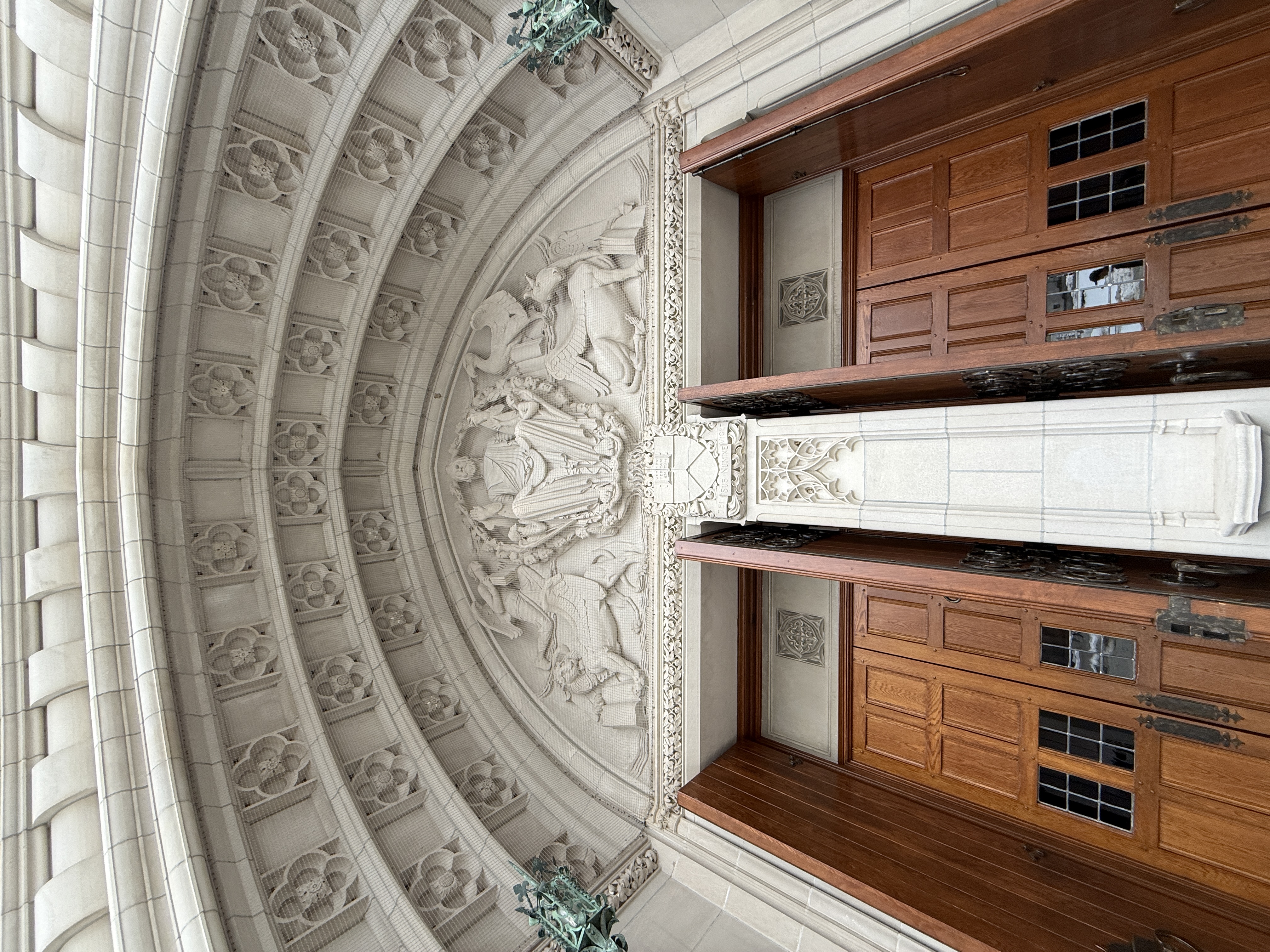Close view of carved stone archway and open wooden chapel doors