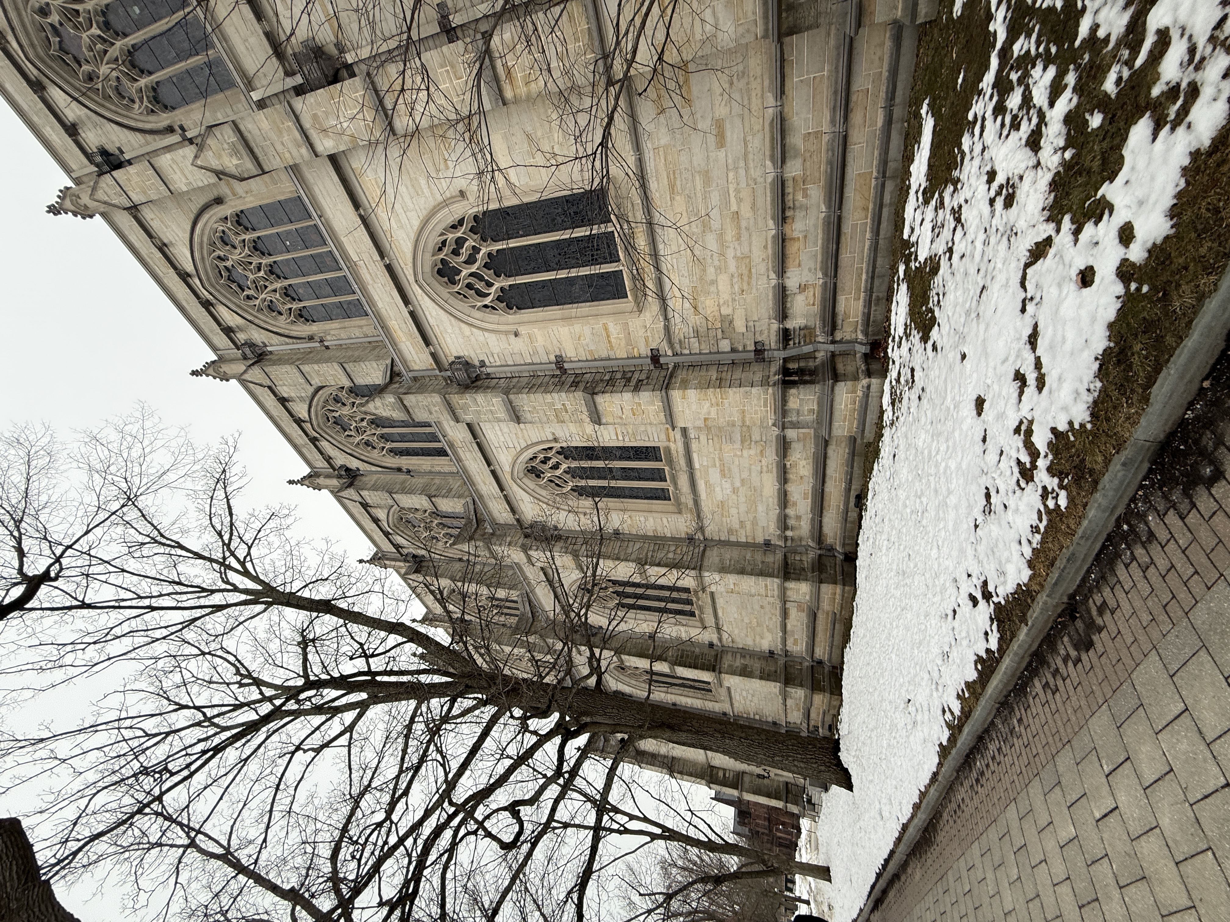 Stone arch framing a tall stained-glass side window on the chapel exterior
