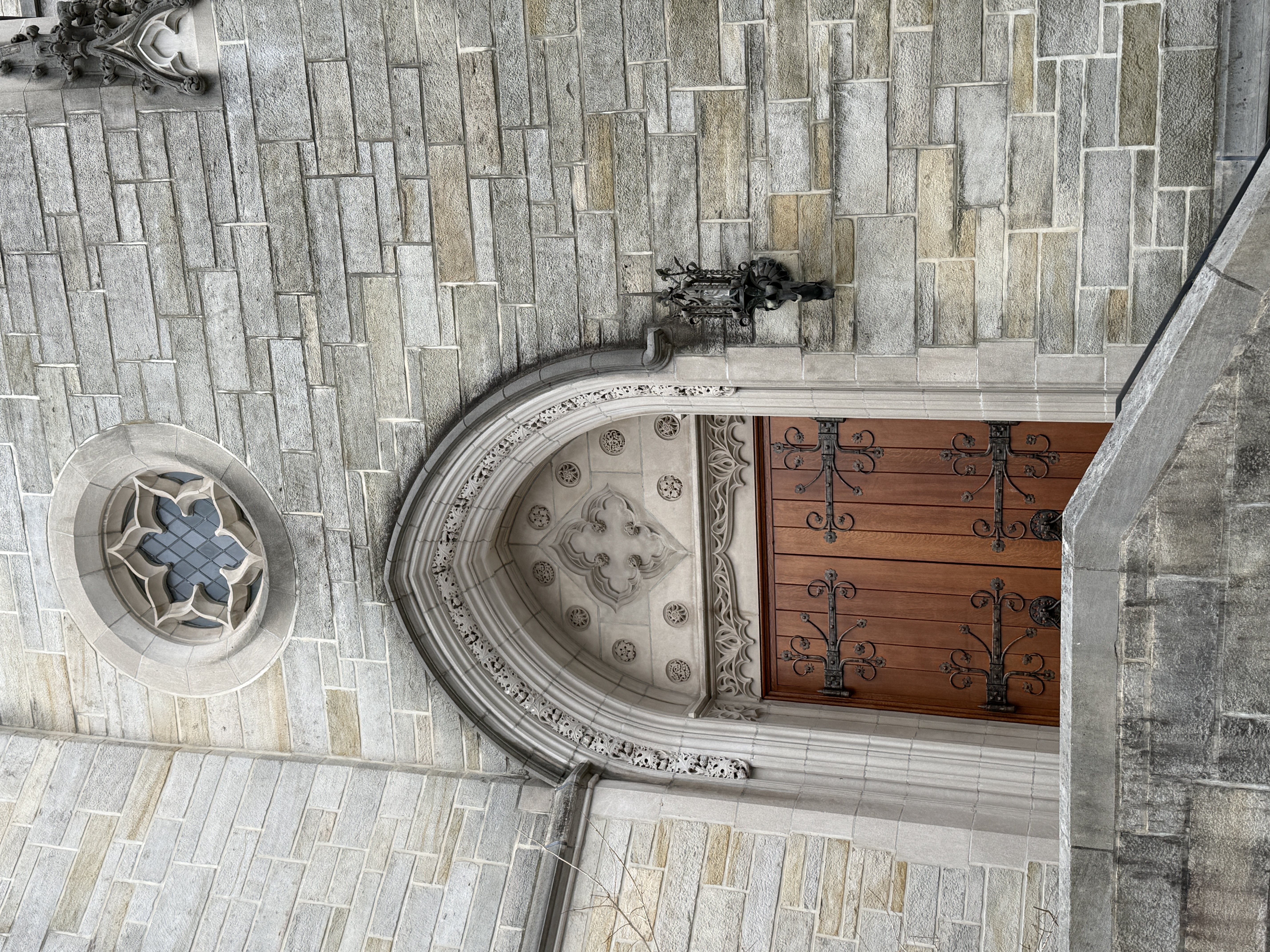 Interior stone stairwell descending beside a dark metal handrail