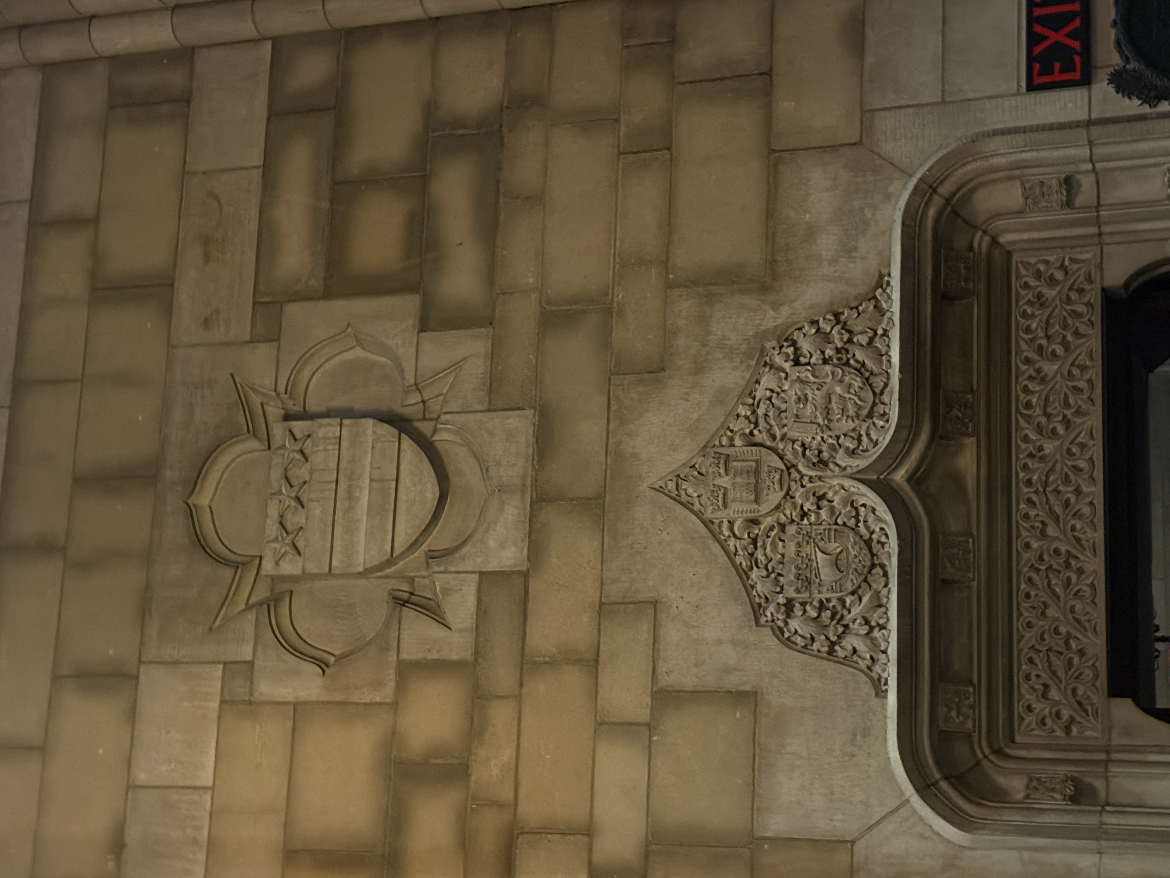 Stone heraldic shield carved with a lion-like creature near an ornate arch