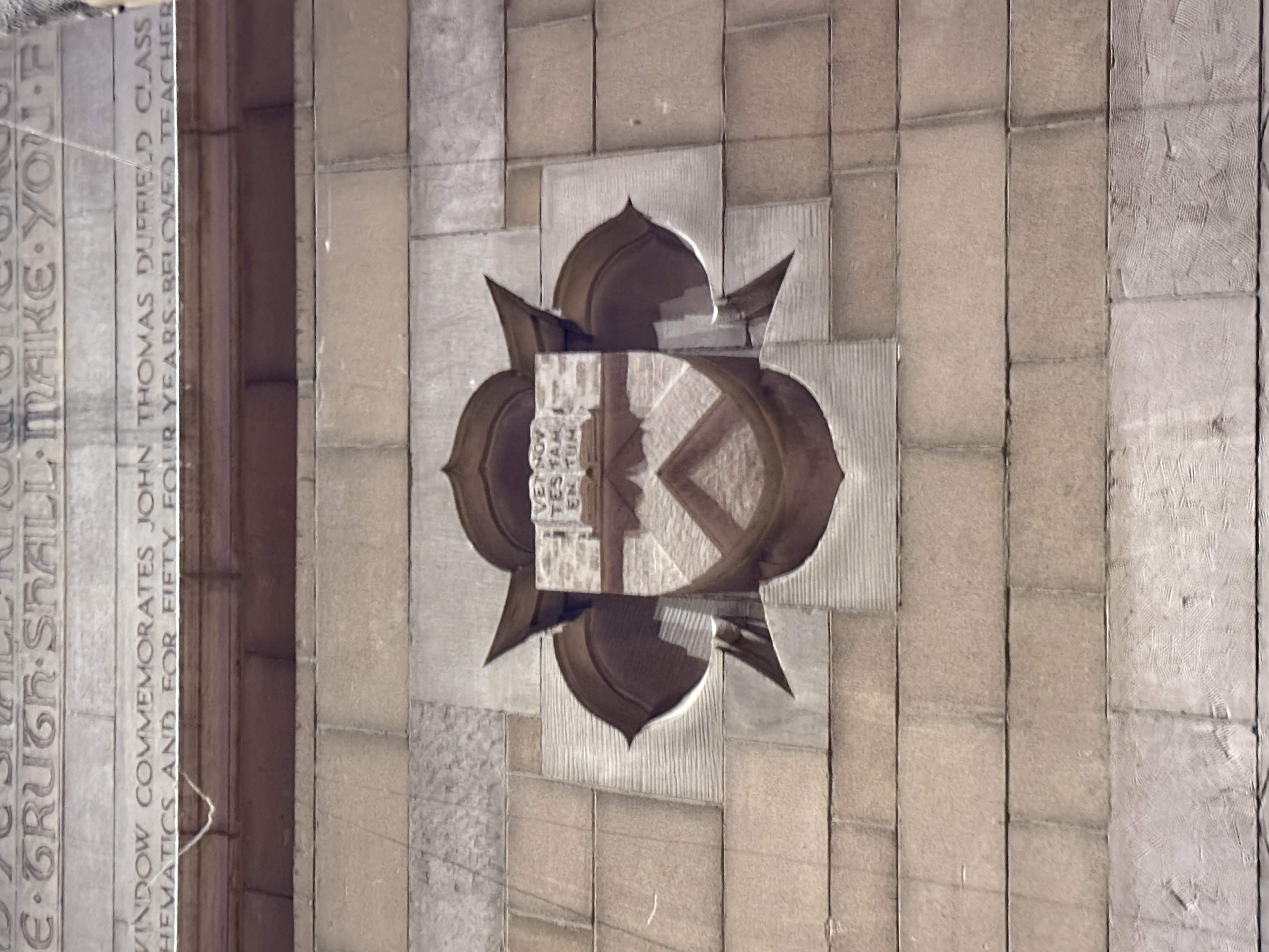 Stone heraldic shield mounted above an engraved memorial inscription