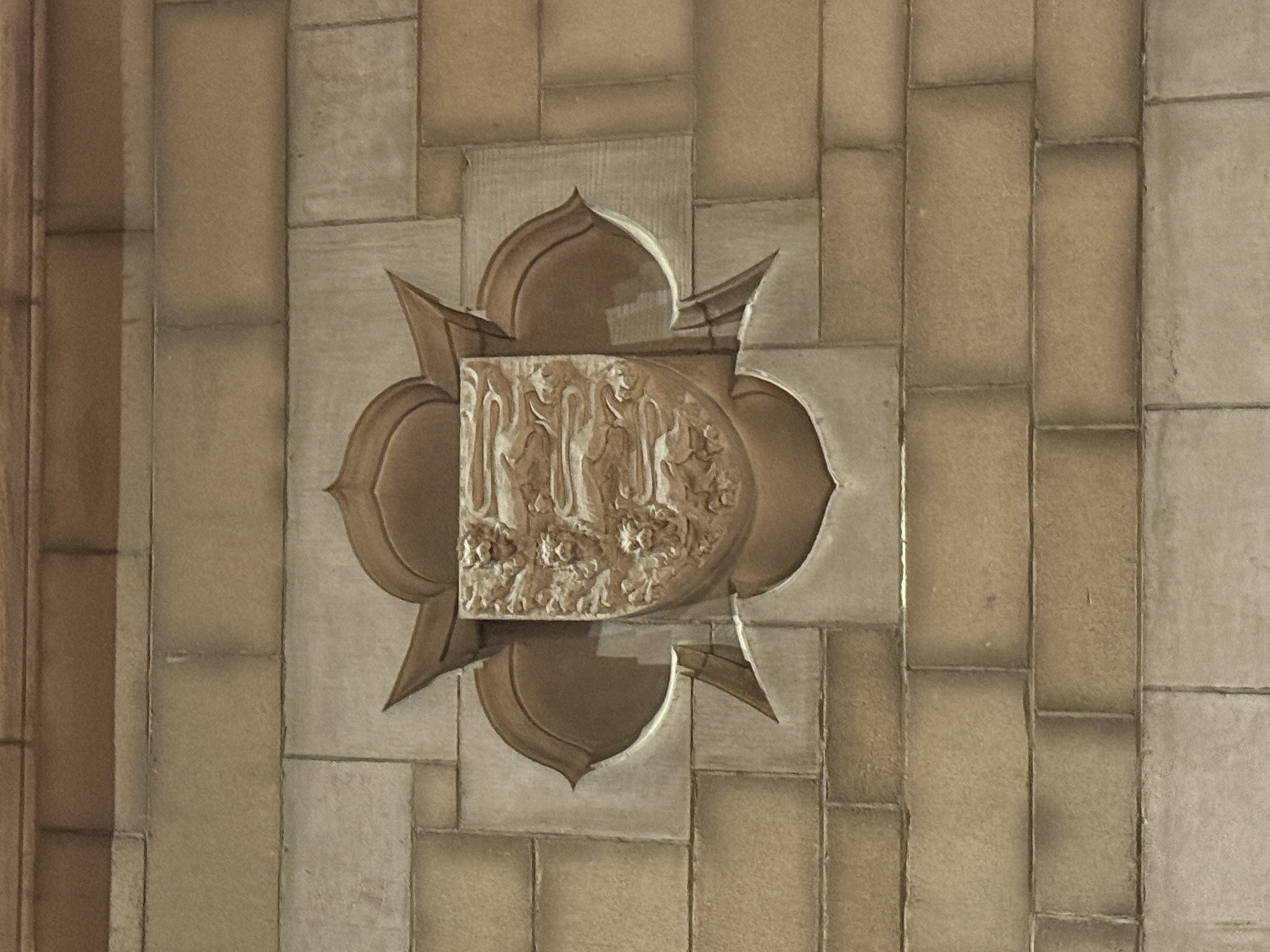 Close-up of a four-part stone shield with worn carved emblems