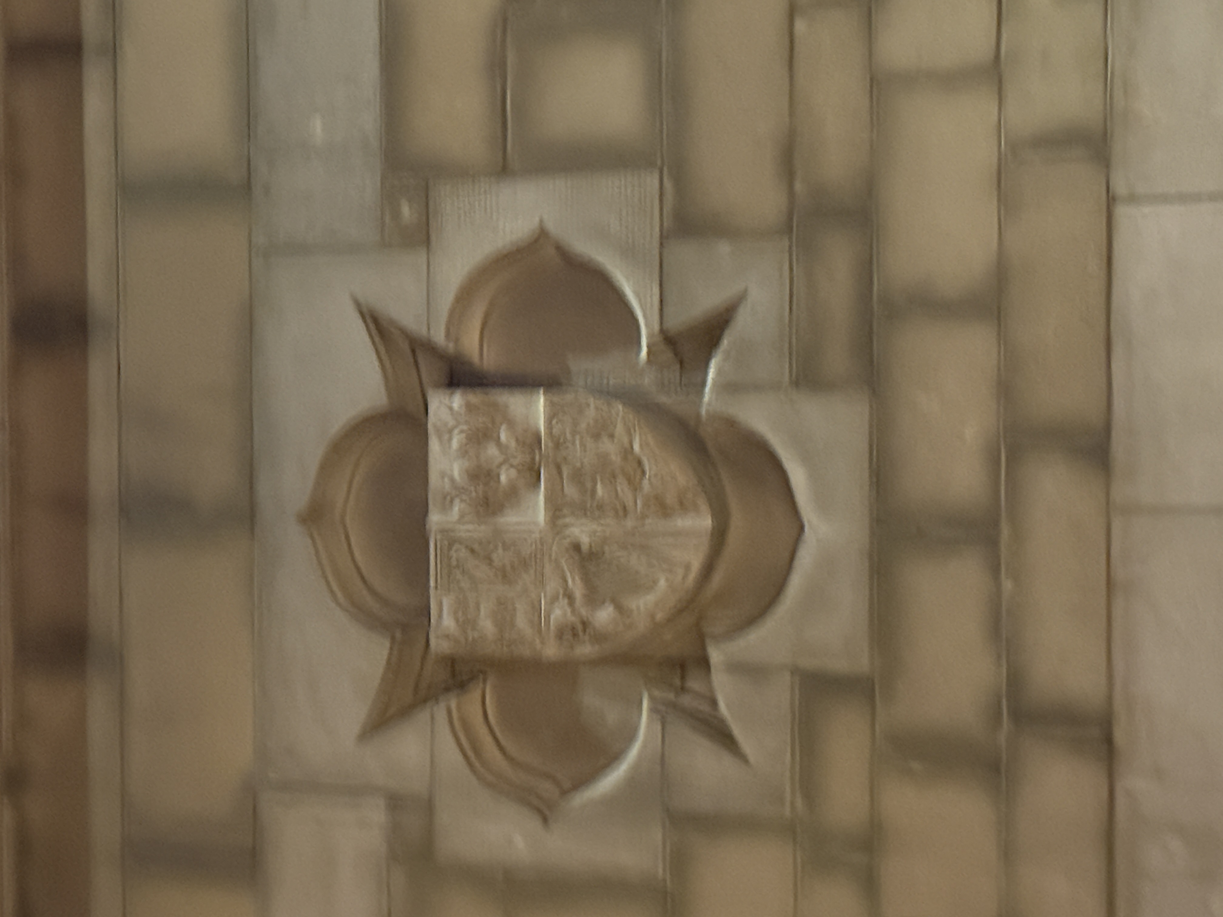 Carved stone crest featuring three vertical serpentine figures above floral details