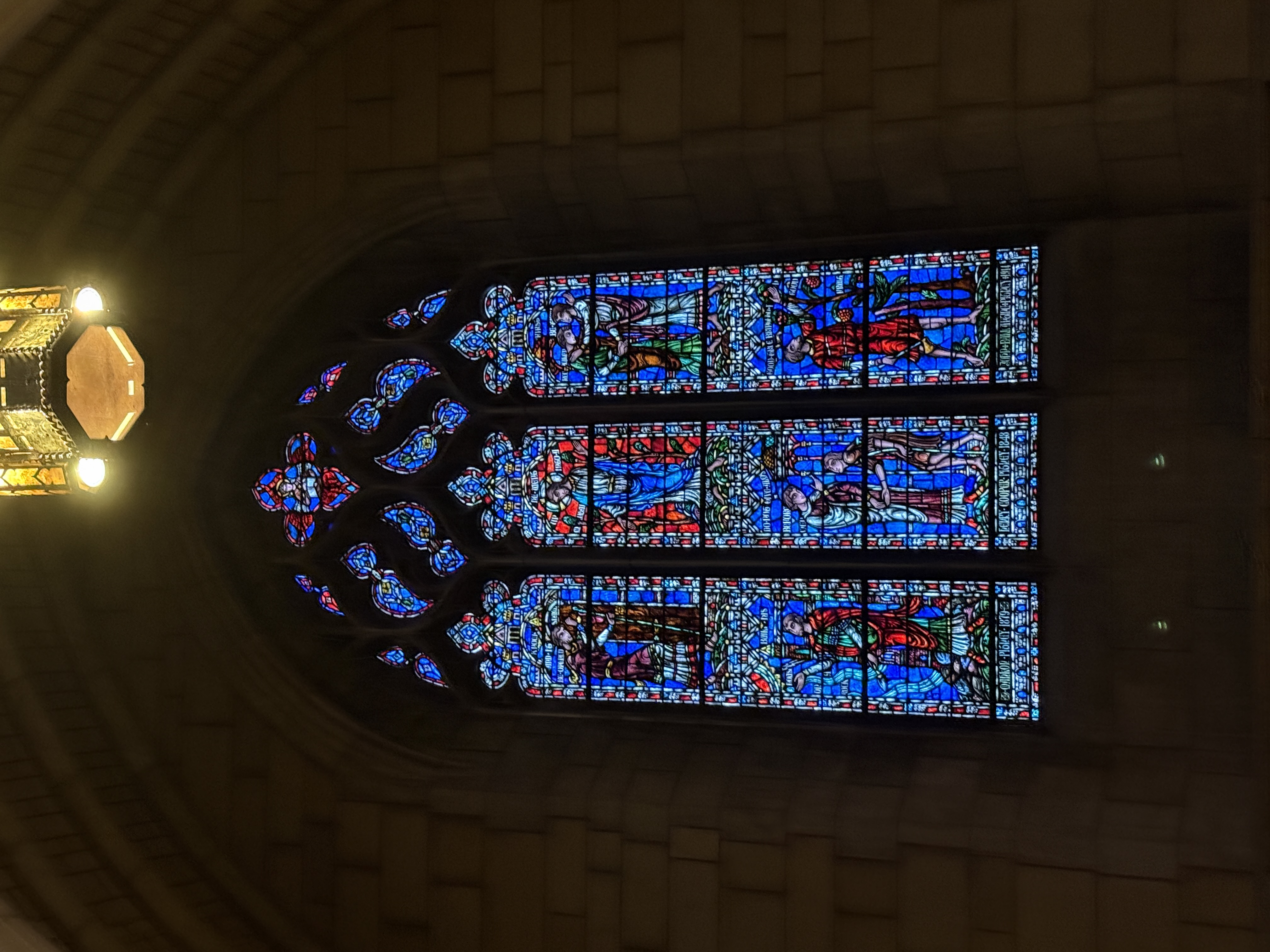 Tall stained-glass window with pale blue panels and saintly figures