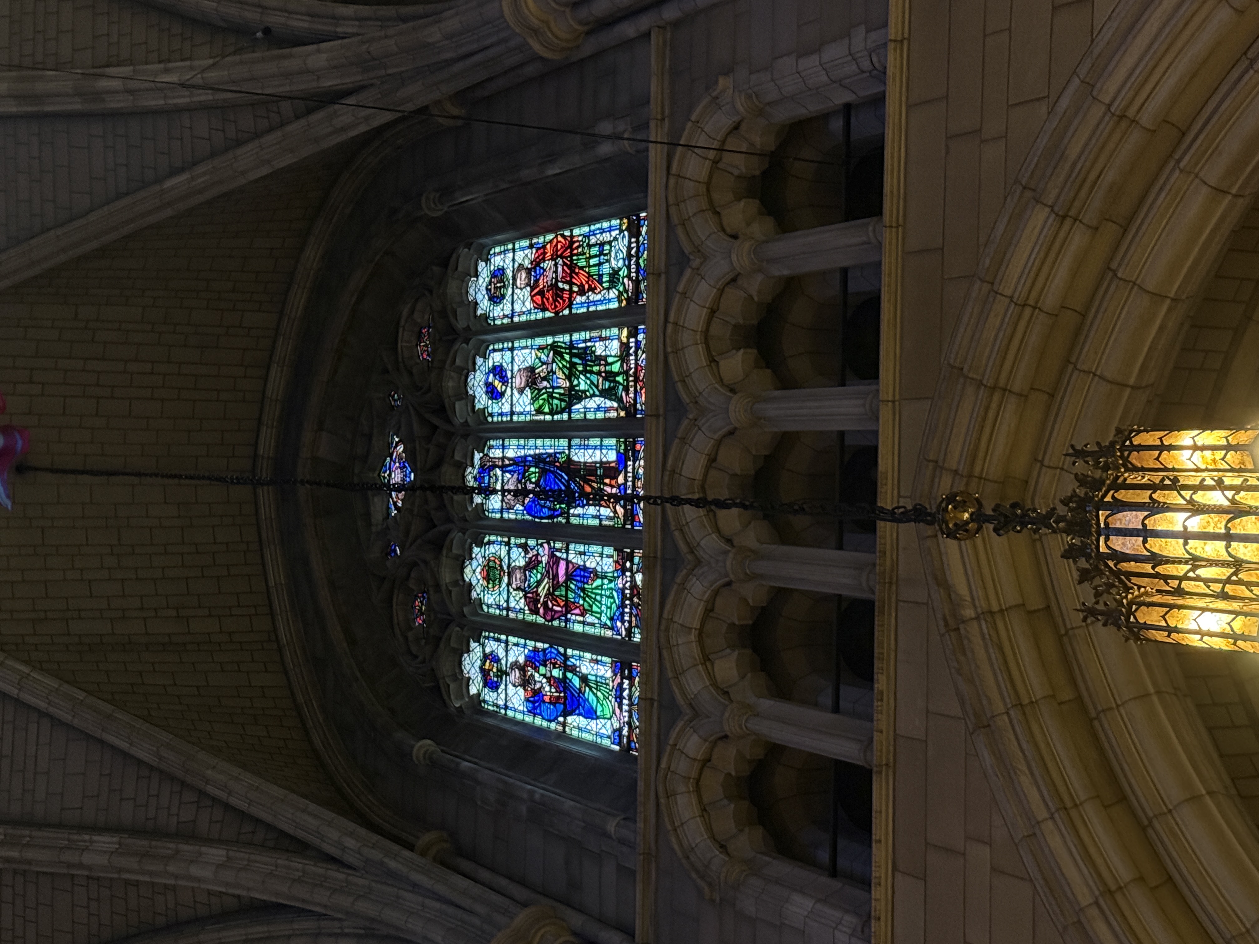 Colorful stained-glass window glowing above stone arches inside the chapel