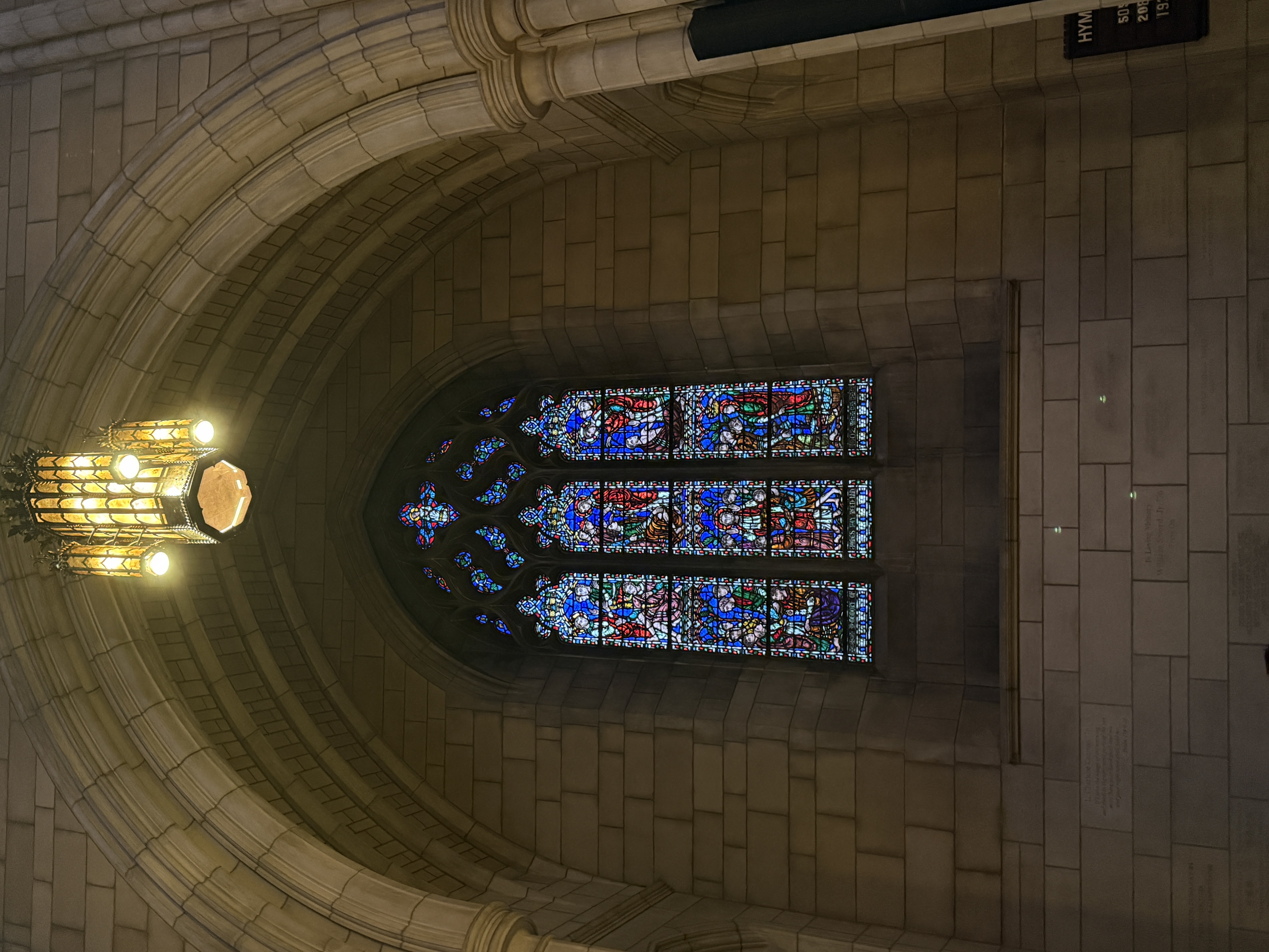 Tall chapel window with stained-glass figures above a carved stone sill