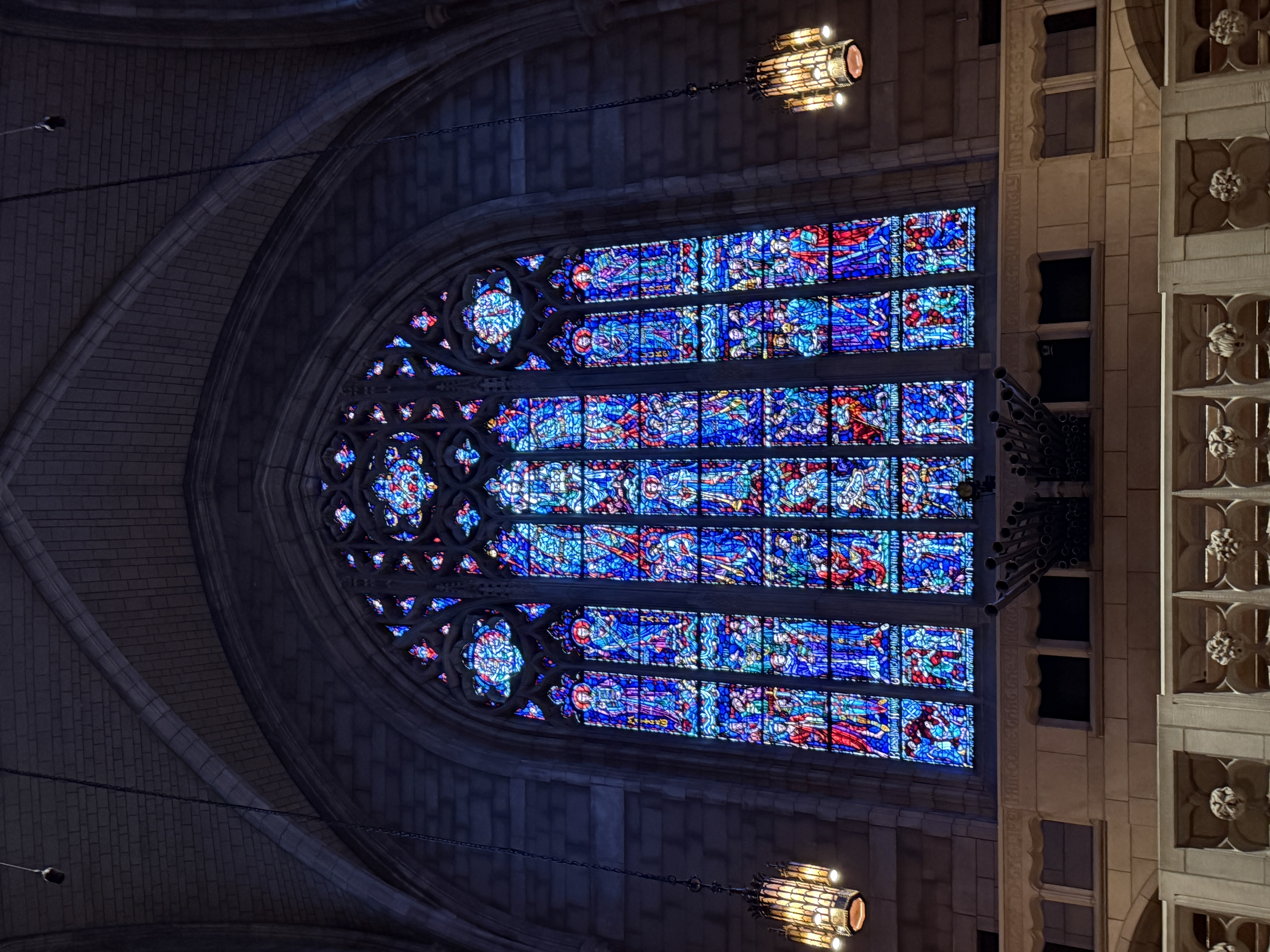 Close-up of stained-glass panels featuring robed figures and patterned borders