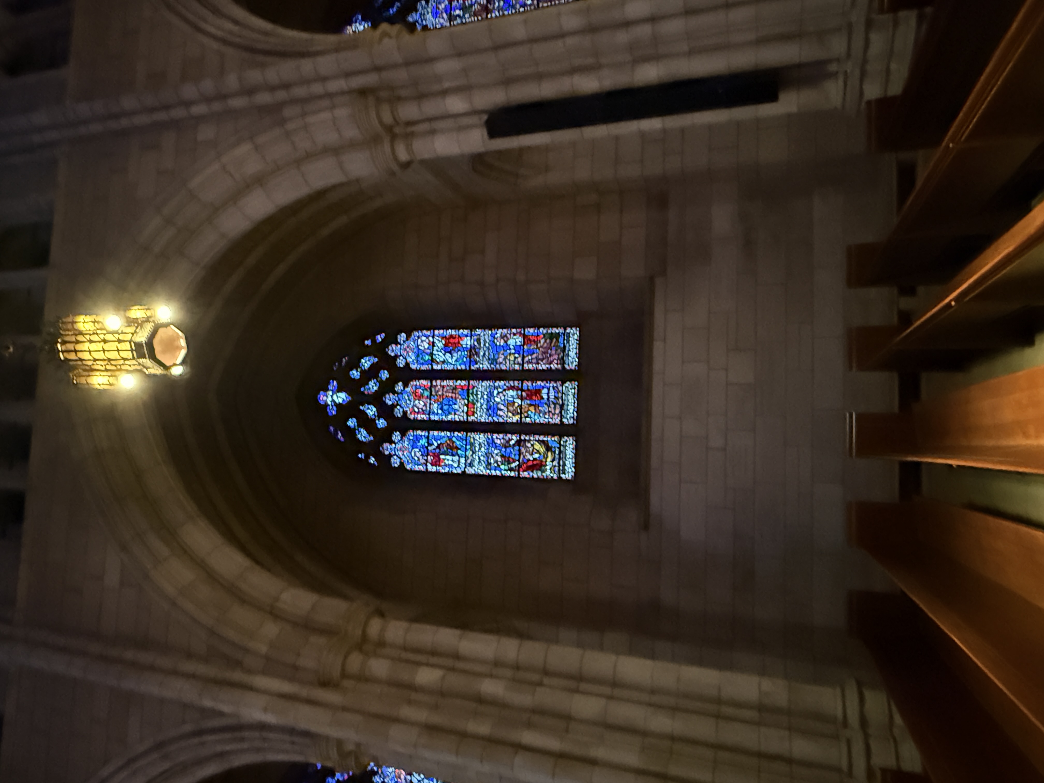 Gothic stained-glass window with three vertical scenes and jewel-toned glass