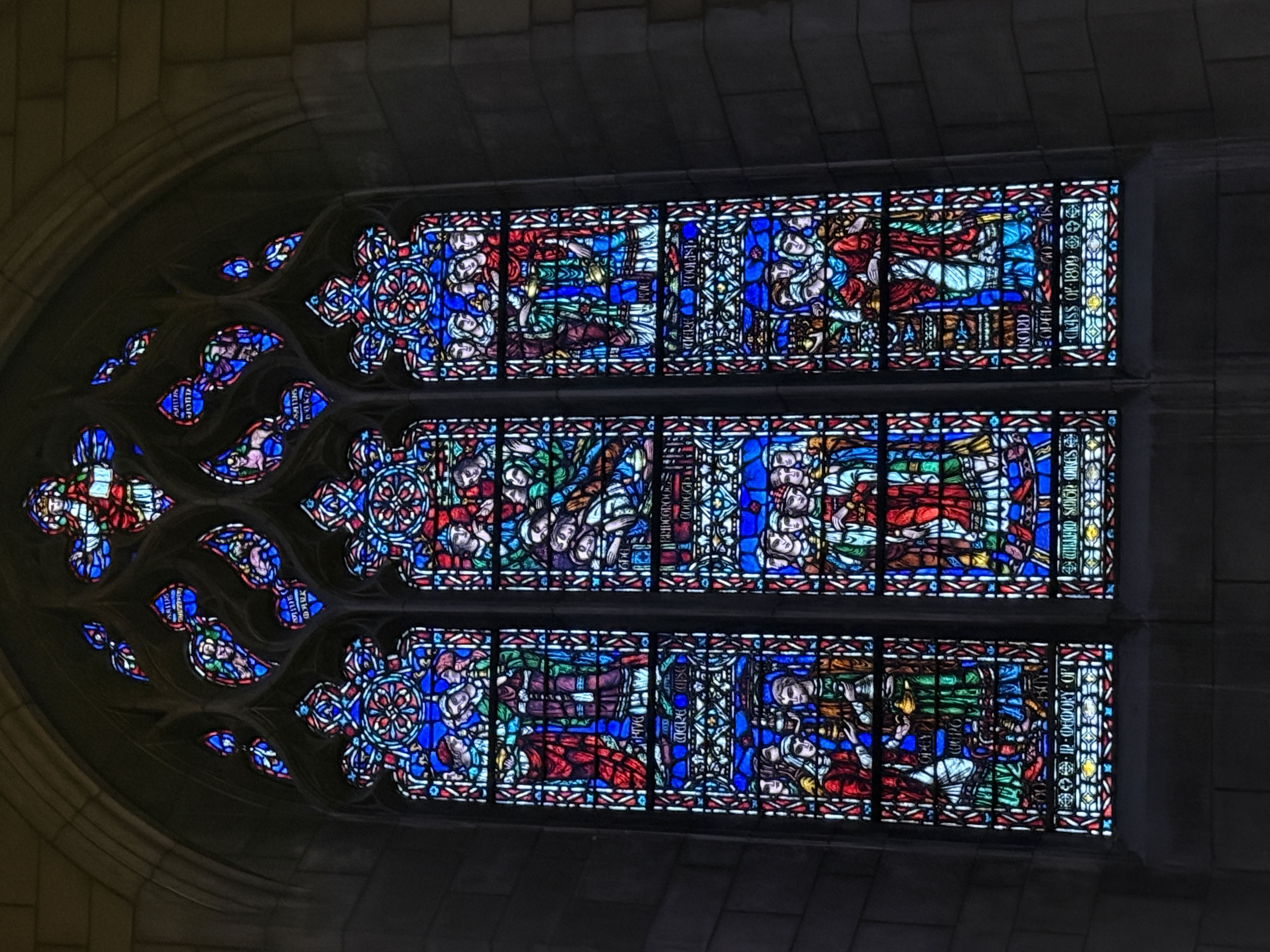 Stained-glass figures seen through the dim interior of the chapel nave