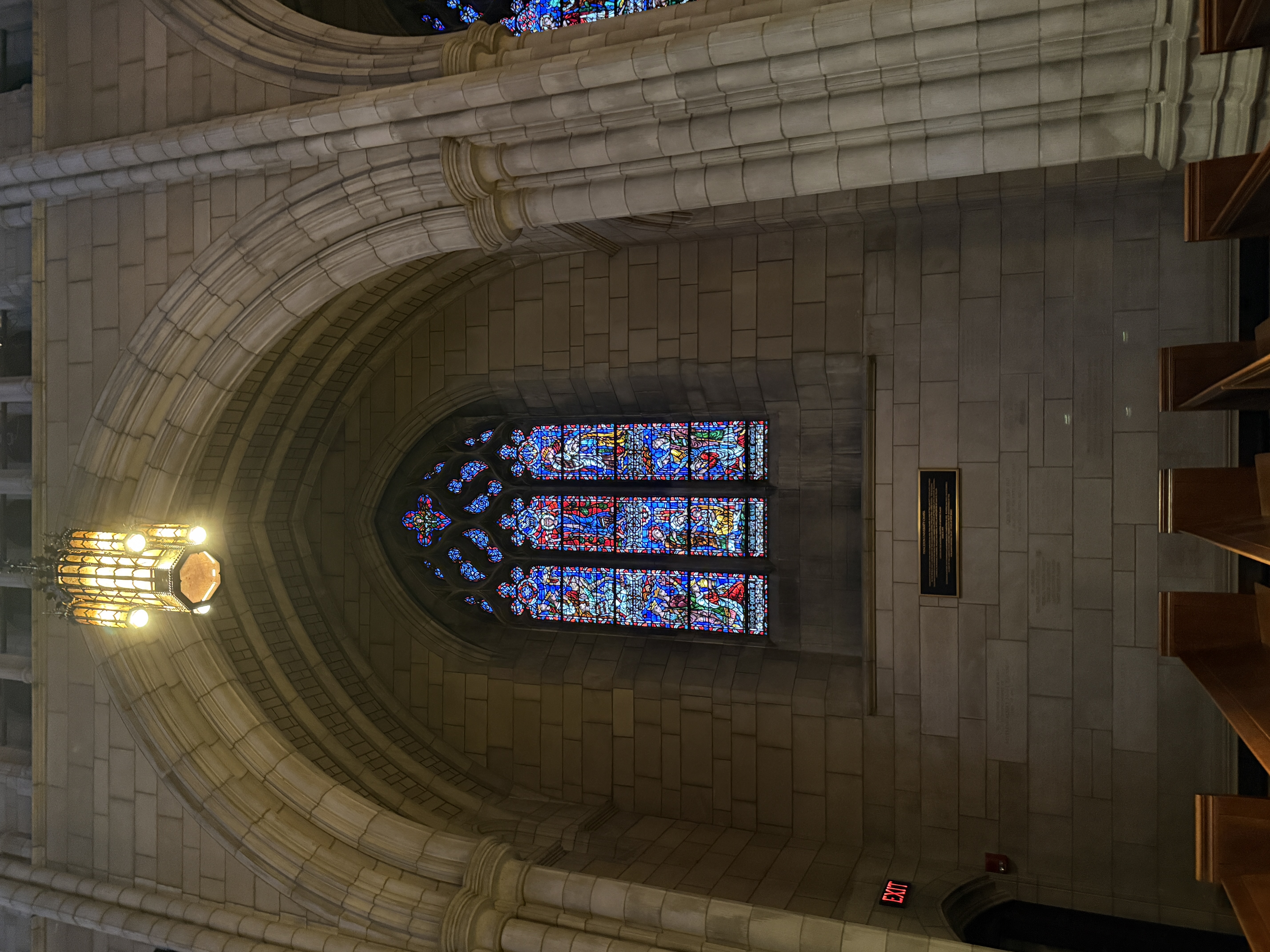 Tall stained-glass window with layered biblical scenes in blue, red, and gold