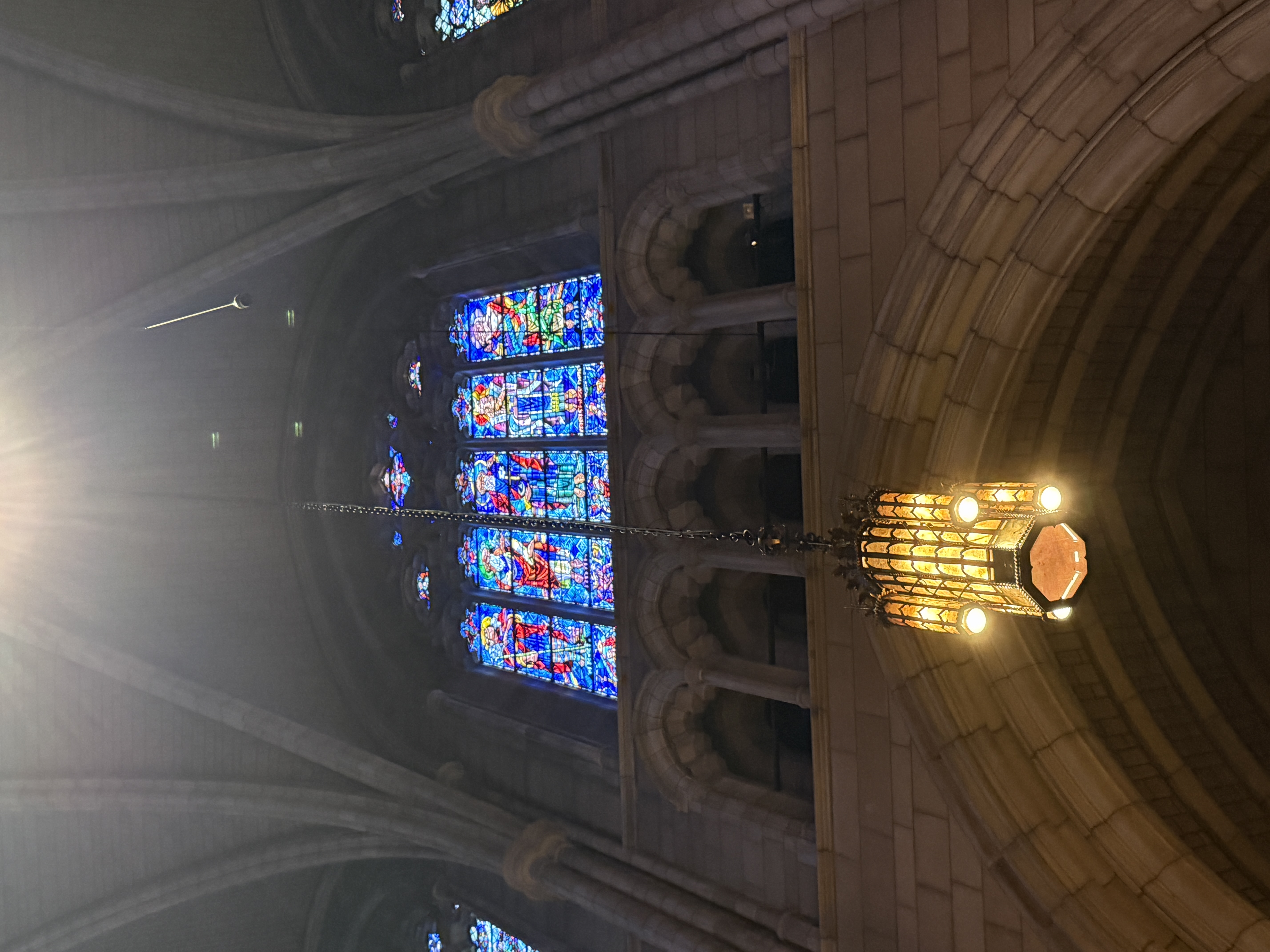 Stained-glass saints and tracery lights framed by a dark stone arch