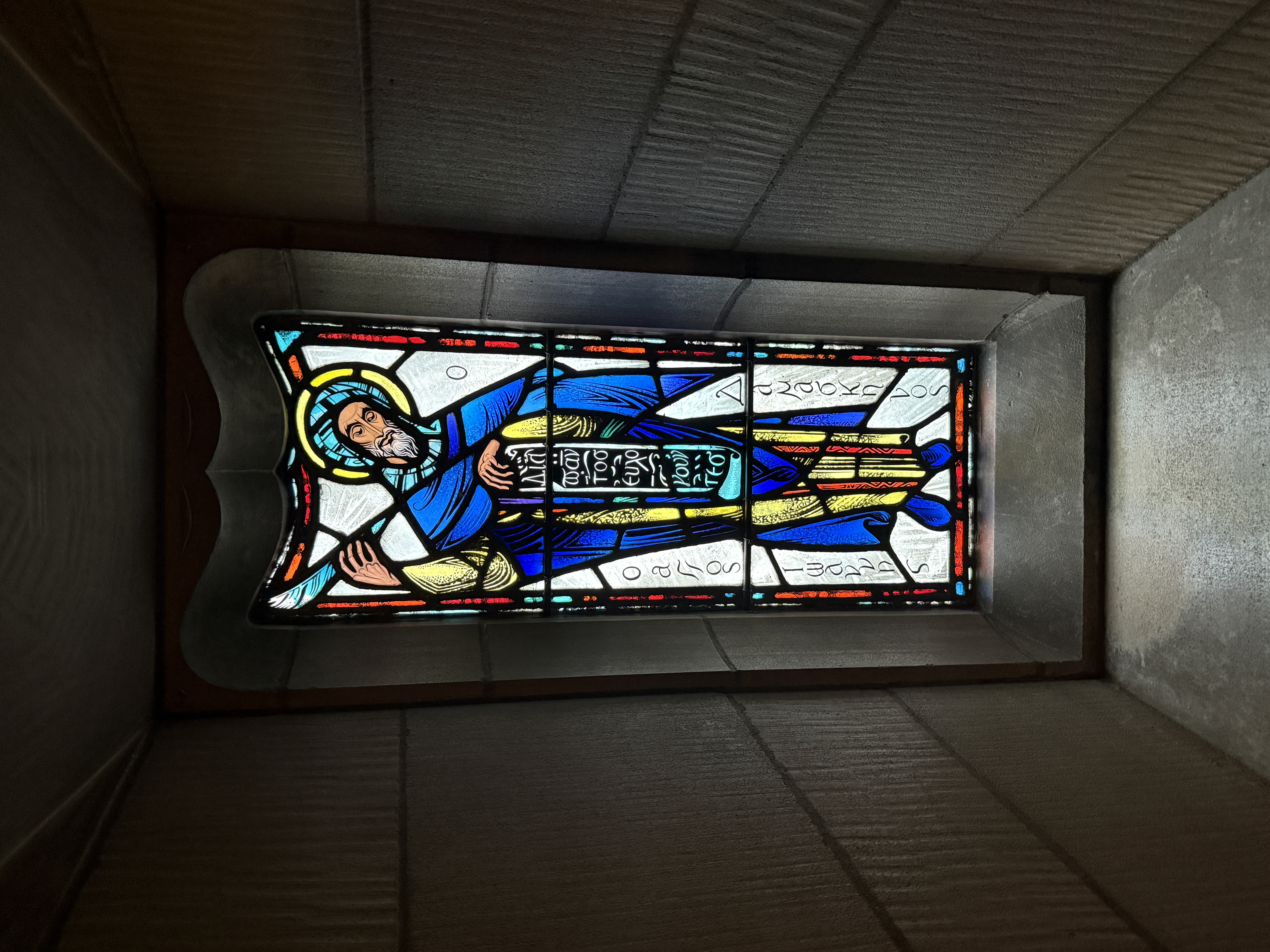 Large figural stained-glass window with three vertical scenes and rich blue glass