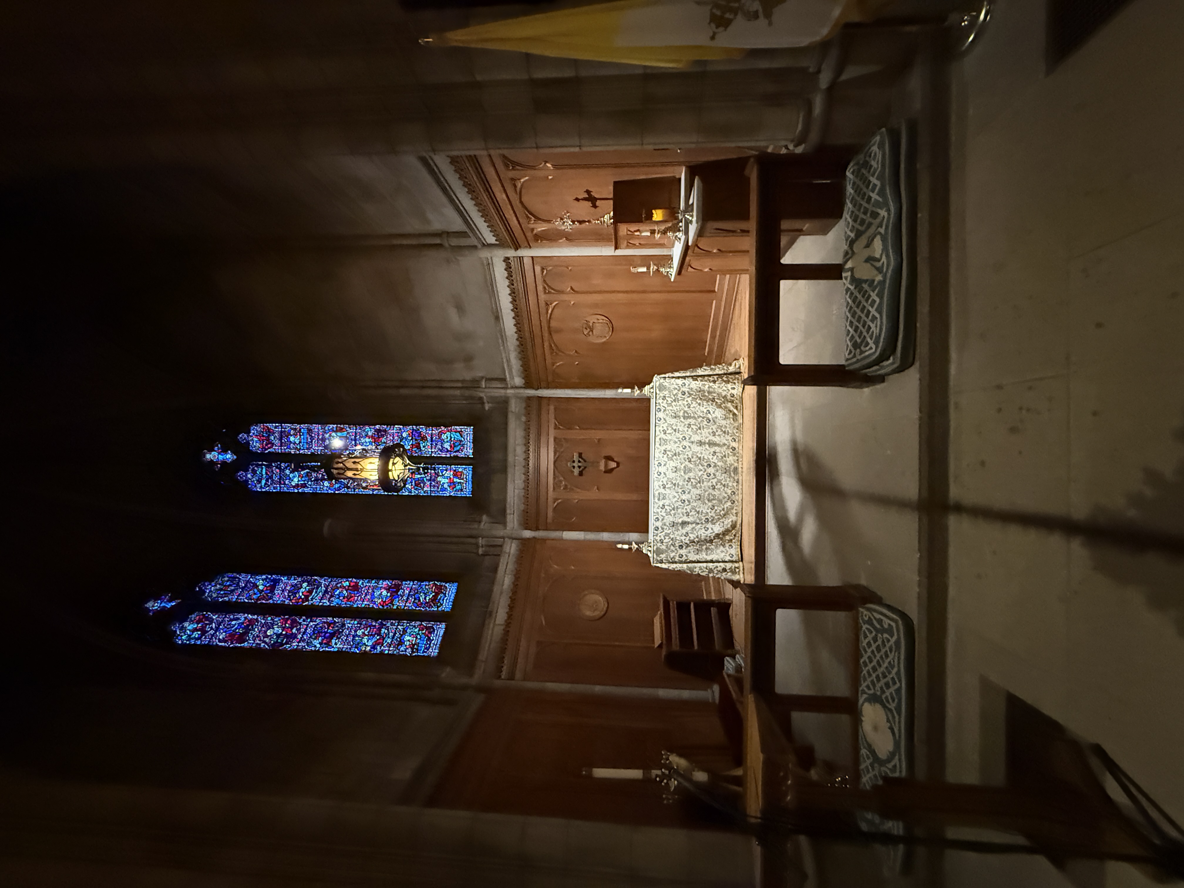 High sanctuary wall lined with large stained-glass windows above choir seating